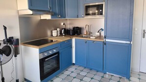 Una cocina compacta con gabinetes azules, un microondas, una estufa y un lavabo.