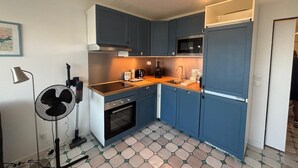 Una cocina compacta con armarios azul oscuro, un microondas, un lavamanos y una estufa.
