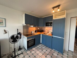 A compact kitchen with dark blue cabinets, a microwave, a sink, and a stove. - Apartment with sea view, terrace and swimming pool (Antibes)