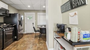 Une cuisine équipée d’un coin café, comprenant une machine à café, des tasses et un panneau indiquant « BAR À CAFÉ ».