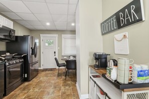 Eine Küche mit einer Kaffeebar, darunter eine Kaffeemaschine, Tassen und ein Schild mit der Aufschrift 'COFFEE BAR'.