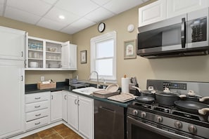 A kitchen with white cabinets, a microwave, a stove, and a sink. - Walk Lakewood - Game Room - King Bed - Sleeps 10 (Lakewood)