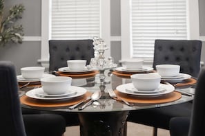 A formal dining table set for eight with white bowls, plates, and cutlery, surrounded by dark upholstered chairs. - Walk Lakewood - Game Room - King Bed - Sleeps 10 (Lakewood)
