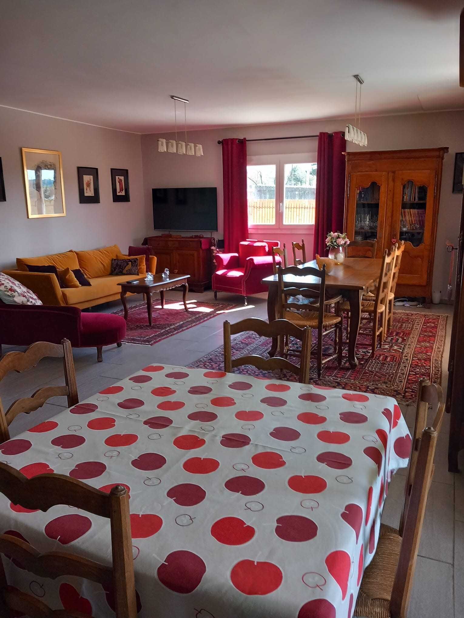 Een woonkamer met een bank, een eettafel, stoelen, een televisie en een boekenkast.
