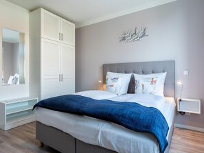 A bedroom with a bed, a wardrobe, a bedside table, and a wall-mounted light fixture. - West Loggia Flat in der Nahe der Kuste (Lübeck)