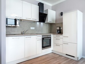 A modern kitchen with white cabinetry, a built-in oven, a microwave, and a coffee maker. - West Loggia Flat in der Nahe der Kuste (Lübeck)