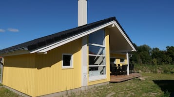 A yellow building with a large window and a chimney.