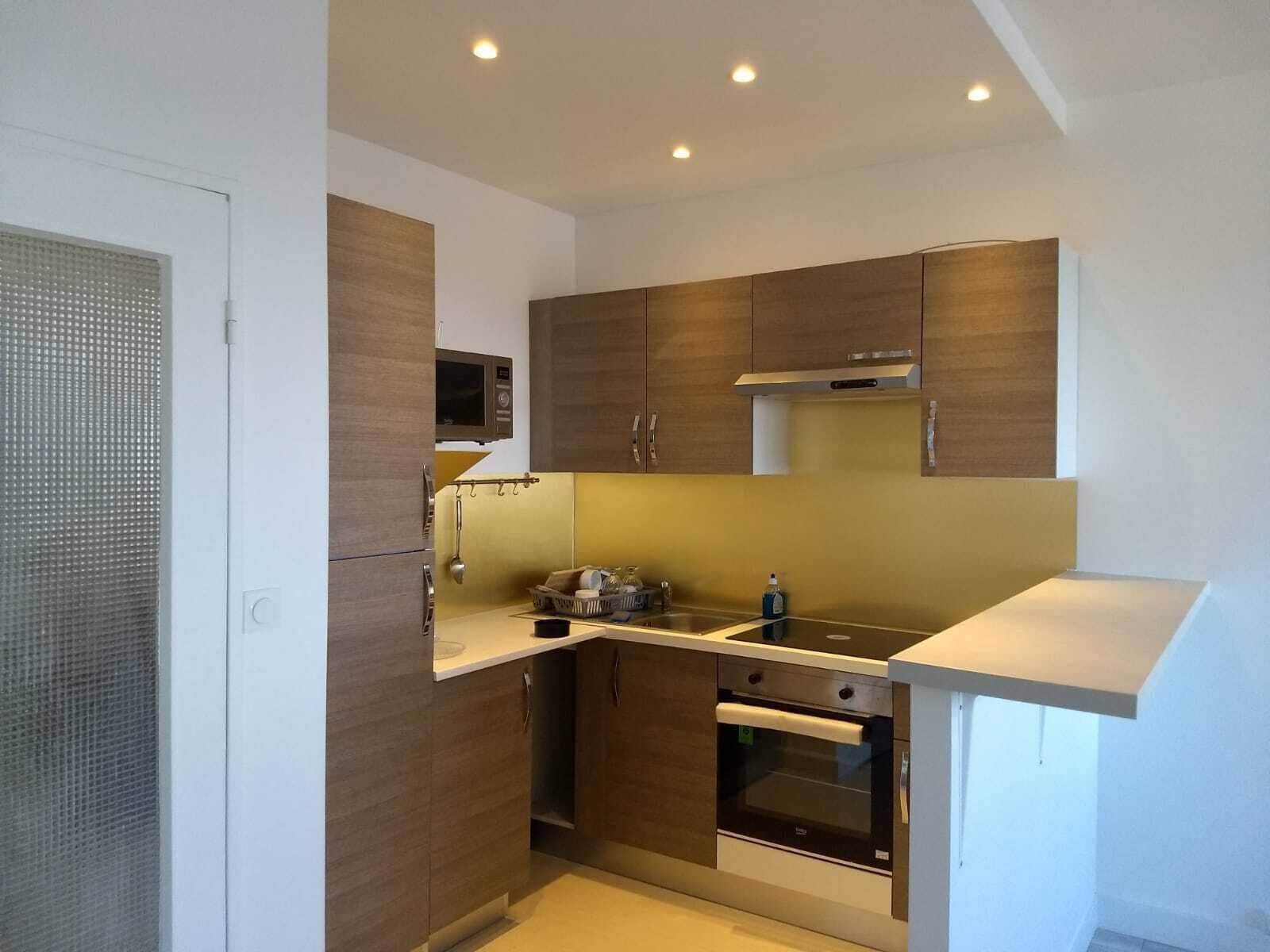 Une cuisine de taille réduite, dotée de meubles en bois, d’un four à micro-ondes, d’une cuisinière et d’un évier.
