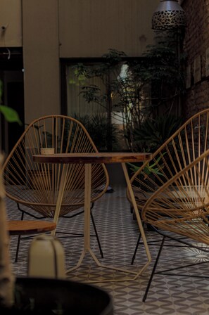 A seating area with wicker chairs and a table, surrounded by potted plants and a patterned floor. - MARCEL – Y'r Own Boutique Hotel in Buenos Aires (Buenos Aires)