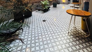 Un espace extérieur aménagé avec des murs en briques, des plantes en pot et un sol à motifs.