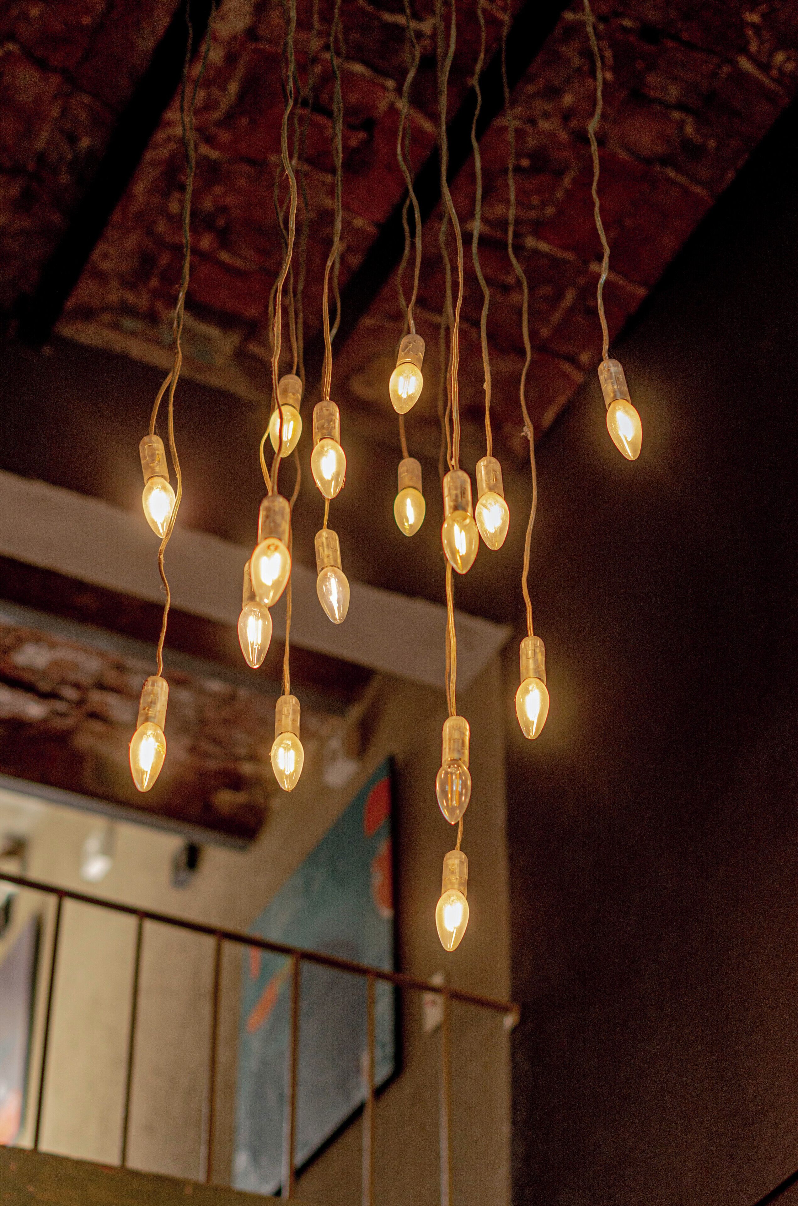 A string of hanging light bulbs in a dimly lit room with a textured ceiling and a blurred background.