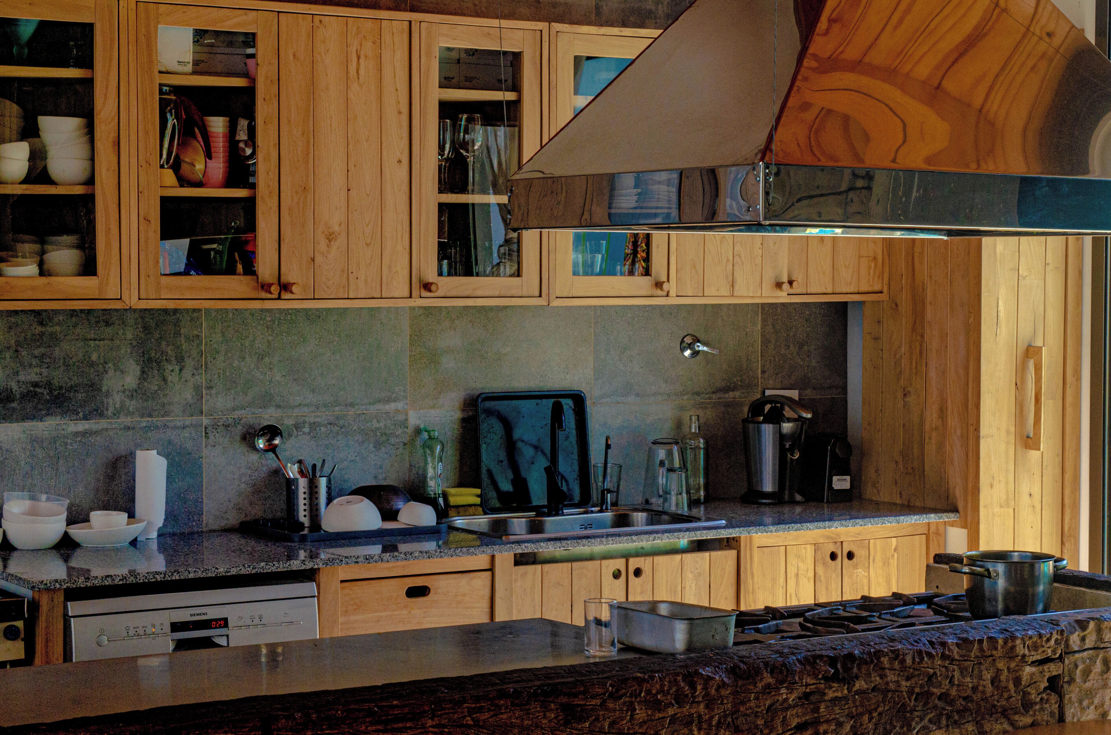 Una cocina con armarios de madera, un lavamanos de acero inoxidable y una campana extractora.