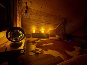 A cozy room with a wooden ceiling, a cowhide rug, and a table with a fan.