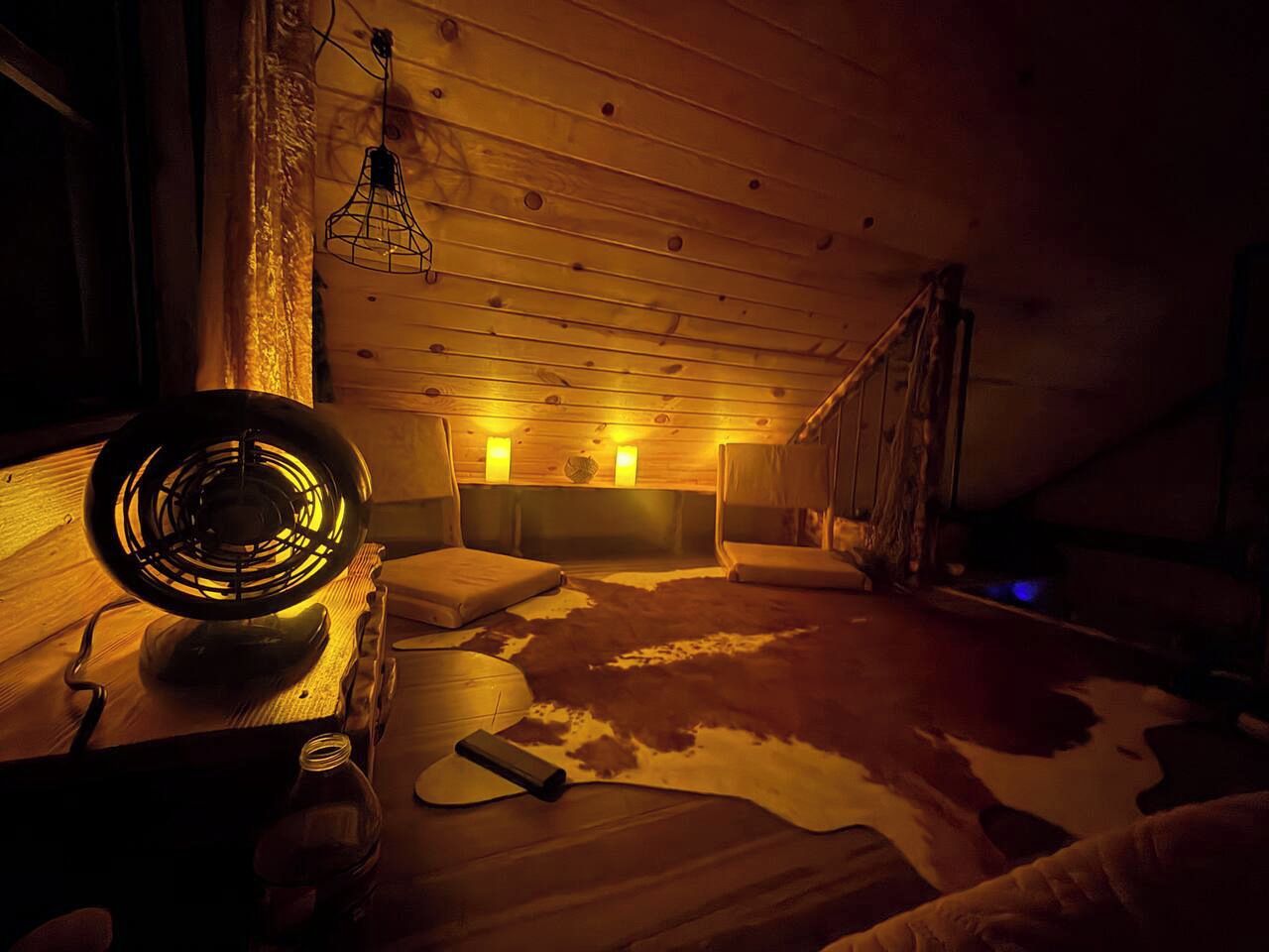 A cozy room with a wooden ceiling, a fur rug, and a vintage fan.