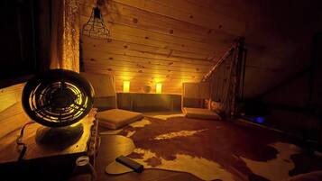 A cozy room with a wooden ceiling, a fur rug, and a vintage fan.