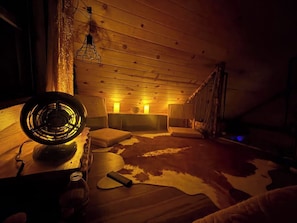 Et hyggeligt værelse med træloft, et pelsunderlag og en vintage ventilator.