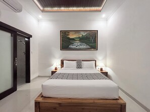 Ein Schlafzimmer mit einem Bett, zwei Nachttischen mit Lampen, einem Bild an der Wand und einem hölzernen Kopfteil.