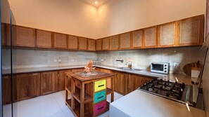 Eine Küche mit Holzausstattung, einem Gasherd, einer Mikrowelle und einem bunten Schrank.