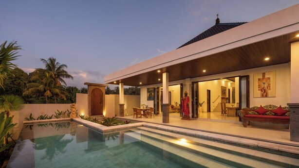 Et moderne hus med swimmingpool, havemøbler og en veloplyst indgang.
