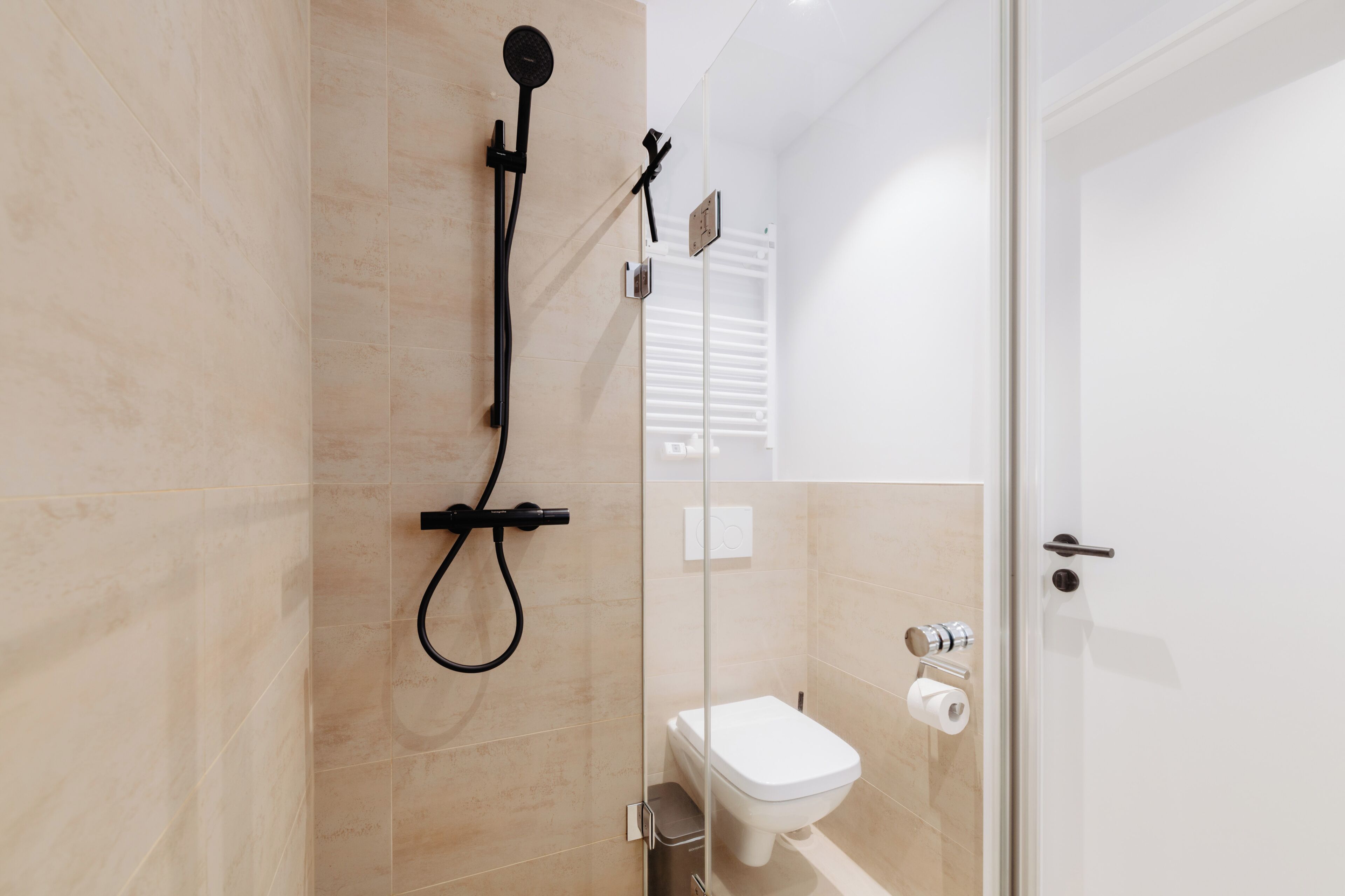 Un baño moderno con ducha, inodoro y puerta de vidrio.
