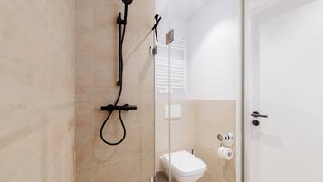 Un baño moderno con ducha, inodoro y puerta de vidrio.