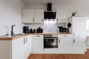 Eine moderne Küche mit weißen Schränken, einer schwarzen Dunstabzugshaube, einer Mikrowelle und einem eingebauten Backofen.