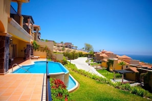 A resort with a swimming pool, terraced buildings, and a view of the ocean. - Pueblo Bonito Montecristo Luxury Villas - All Inclusive (Cabo San Lucas)