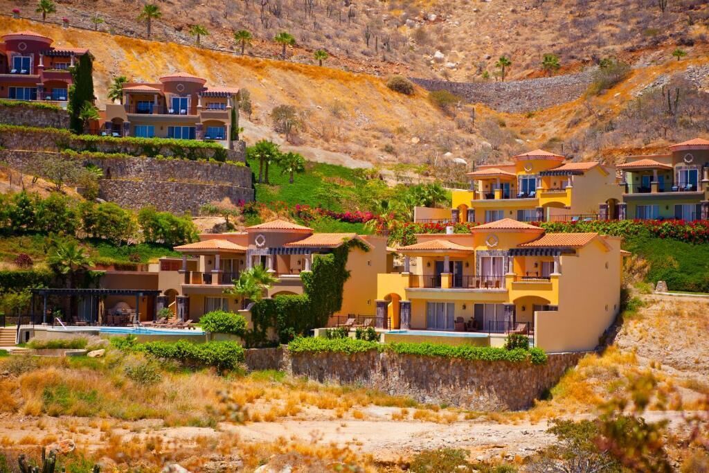 A hillside residential area with multiple two-story houses featuring red-tiled roofs and balconies.