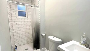 Une salle de bain avec douche, toilettes et lavabo.