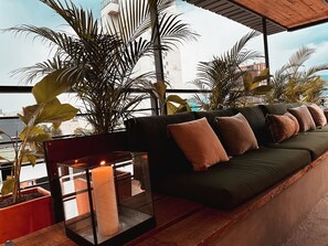 A modern outdoor seating area with a sofa, cushions, and a candle in a glass container. - Luxury penthouse Provenza (Medellín)