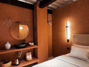 A modern bedroom with a large bed, a round mirror, a bedside table with a kettle, and a wall-mounted light. - Luxury penthouse Provenza (Medellín)