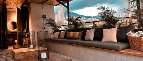 A modern outdoor seating area with a sofa, a wooden table, and a lamp.