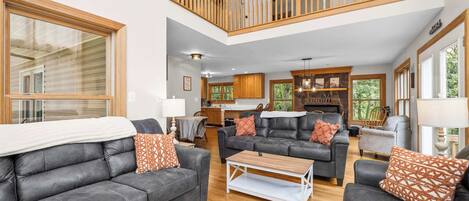 A spacious living room with leather sofas, a coffee table, and a fireplace.