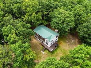 A two-story house with a green roof, surrounded by dense green trees. - Paw Paw Mountain Lodge w/River Access & Fire Pit (Paw Paw)