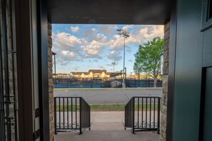 Ein Eingang zu einer Sportanlage mit Blick auf ein Baseballfeld, einer überdachten Sitzgelegenheit und einer Steinmauer.