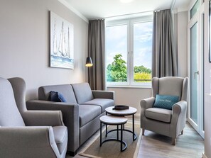 Ein modernes Wohnzimmer mit Sofa, Sessel und einem kleinen Tisch.