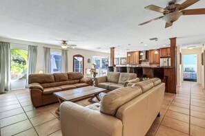 A spacious living room with leather sofas, a wooden coffee table, and a ceiling fan. - Private pool home a bike ride to Siesta Key beach (Siesta Key)
