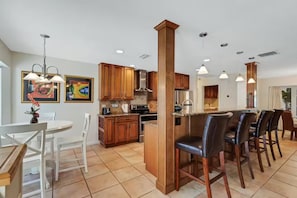 A modern kitchen with wooden cabinets, a central island, and bar-style seating.