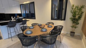 A modern dining area with a round table, black chairs, and a central bowl. - New T3 Villa in Santa Luzia - 3 en-suite bedrooms, 15 minutes from Old Town (Funchal)