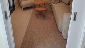 A compact living space with a sofa, a small wooden table, and a ceiling-mounted air conditioning unit. - New T3 Villa in Santa Luzia - 3 en-suite bedrooms, 15 minutes from Old Town (Funchal)