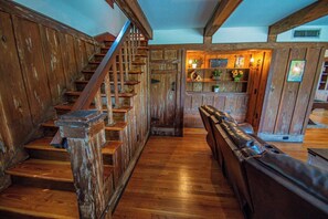 Un escalier en bois mène à un espace détente où se trouvent un banc en bois et un mur en bois doté d’étagères.