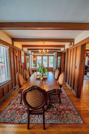 A dining area with a long wooden table, multiple chairs, and a patterned rug. - Historic Charm: Spacious Home w/ Fenced Yard - 3BR/2BA Near Downtown (St. Augustine)