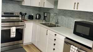 Una cucina moderna con mobili bianchi, elettrodomestici in acciaio inossidabile e una parete backsplash rivestita in piastrelle.