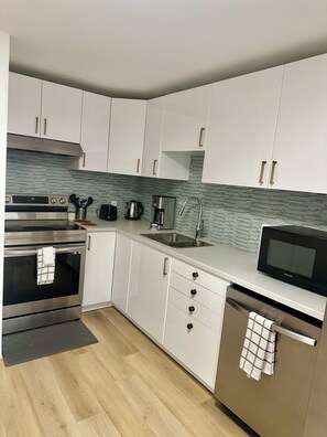 A modern kitchen with white cabinets, stainless steel appliances, and a tiled backsplash. - Condo moderne au cœur de Gatineau – À 2mn de A50 et 20 min d'Ottawa (Gatineau)