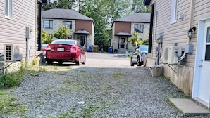 Viale residenziale con due auto parcheggiate, fondo in ghiaia e case dall'architettura simile.