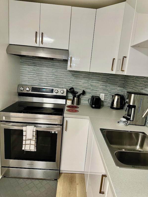 A kitchen with stainless steel appliances, white cabinets, a coffee maker, and a sink.