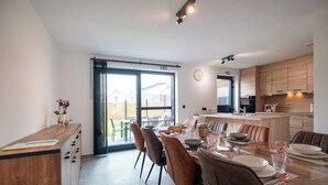 Een moderne keuken met een eethoek, met een groot raam, houten keukenkastjes en een centraal keukenblok.