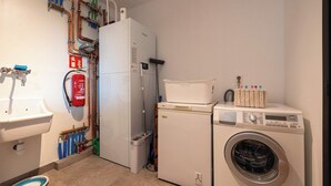 Een kleine wasruimte met een wasmachine, een droger, een wasbak en een brandblusser.