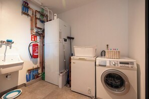 Ein kleiner Waschraum mit Waschmaschine, Trockner, Spüle und Feuerlöscher.