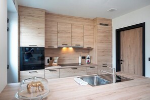 Eine moderne Küche mit Holzschränken, einer Edelstahlspüle und einem eingebauten Backofen.